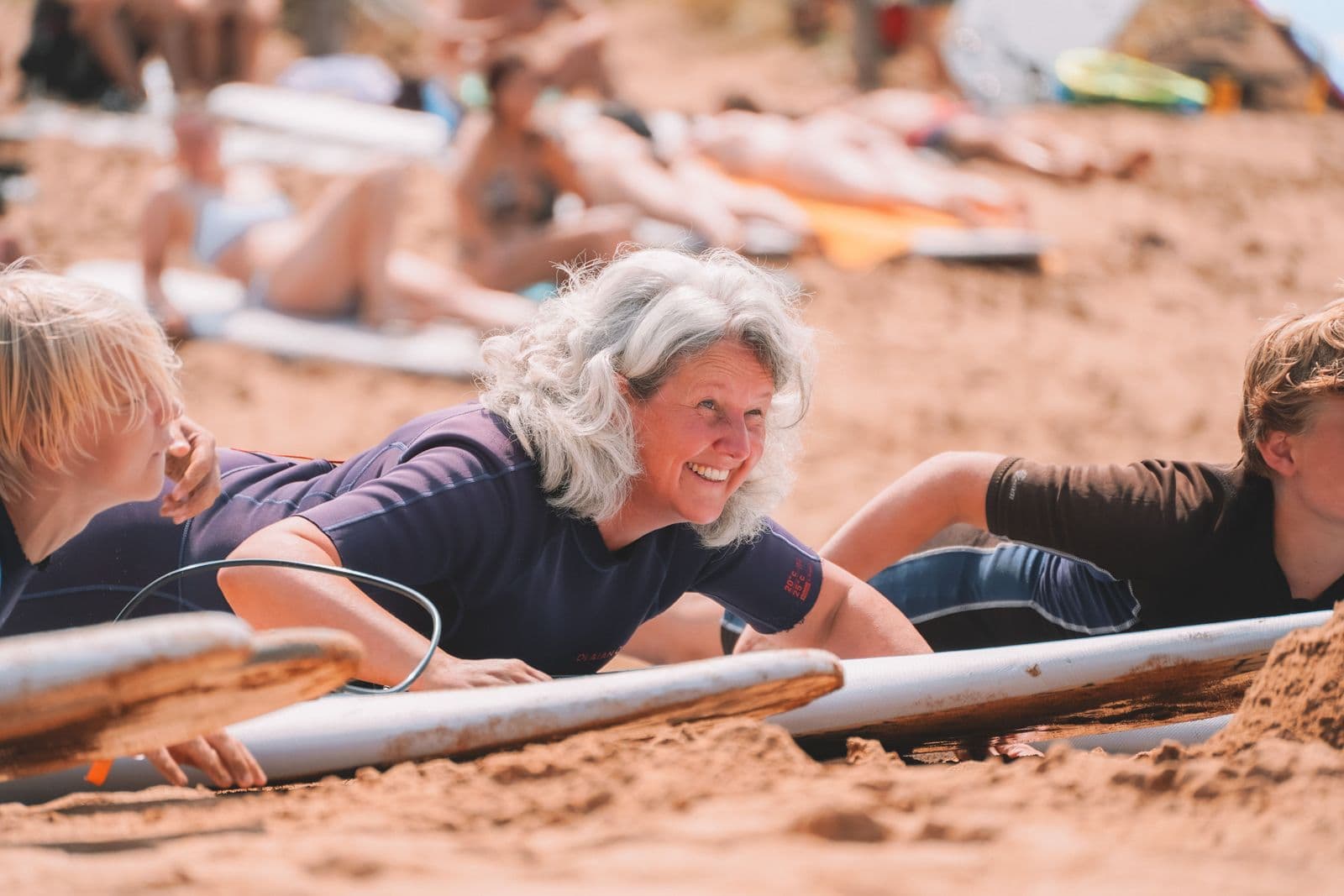 Vrouw met grijs haar ligt op een surfboard